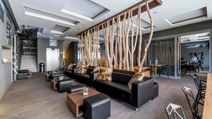 A modern lounge area with sofas, a coffee table, and a wooden decorative structure. - Hotel Pecr Well (Pec pod Snezkou)