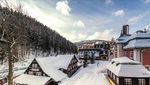 A snow-covered village with traditional buildings, including a hotel with a sign indicating it is a hotel. - Hotel Pecr Well (Pec pod Snezkou)