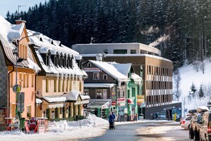 Una calle cubierta de nieve con edificios, incluyendo un restaurante y una estructura moderna.