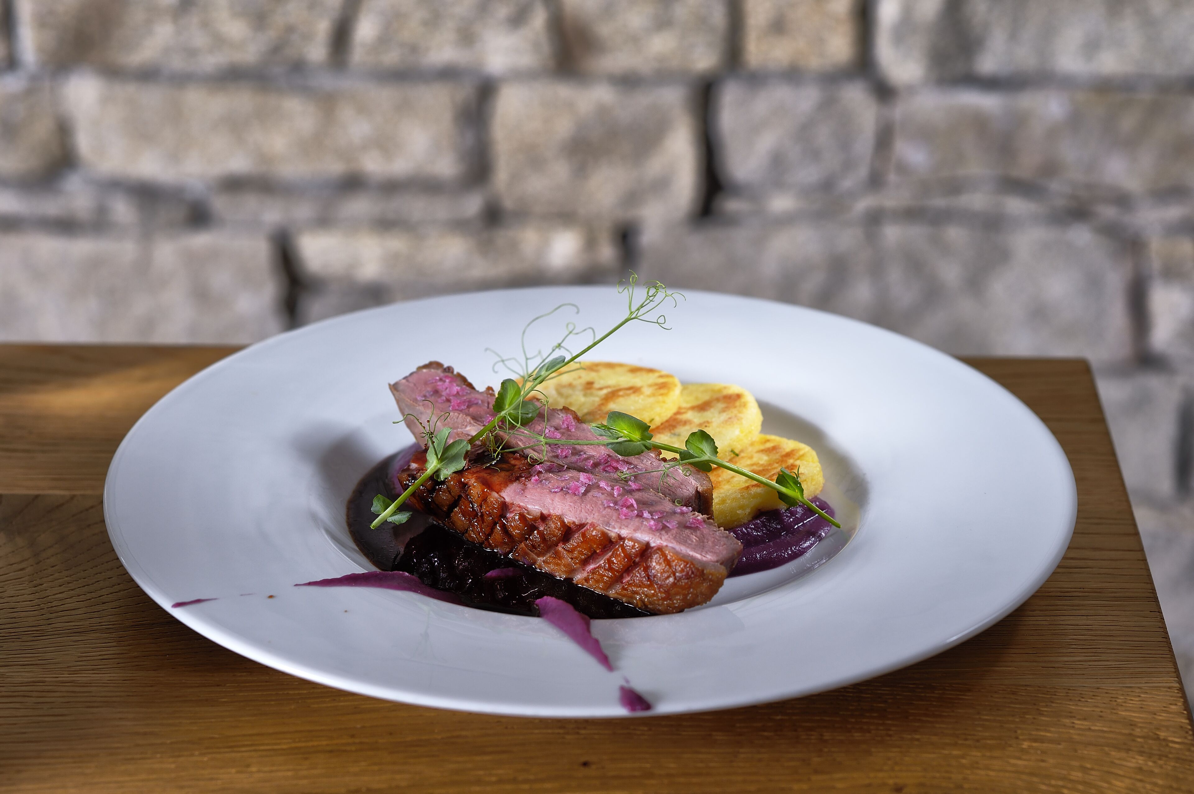 A plate of food with a piece of meat, vegetables, and a small green garnish.