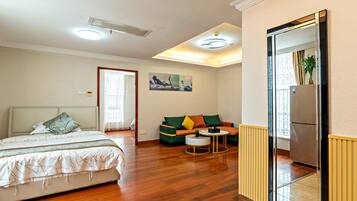A bedroom with a bed, a sofa, a small round table, and a mirror.