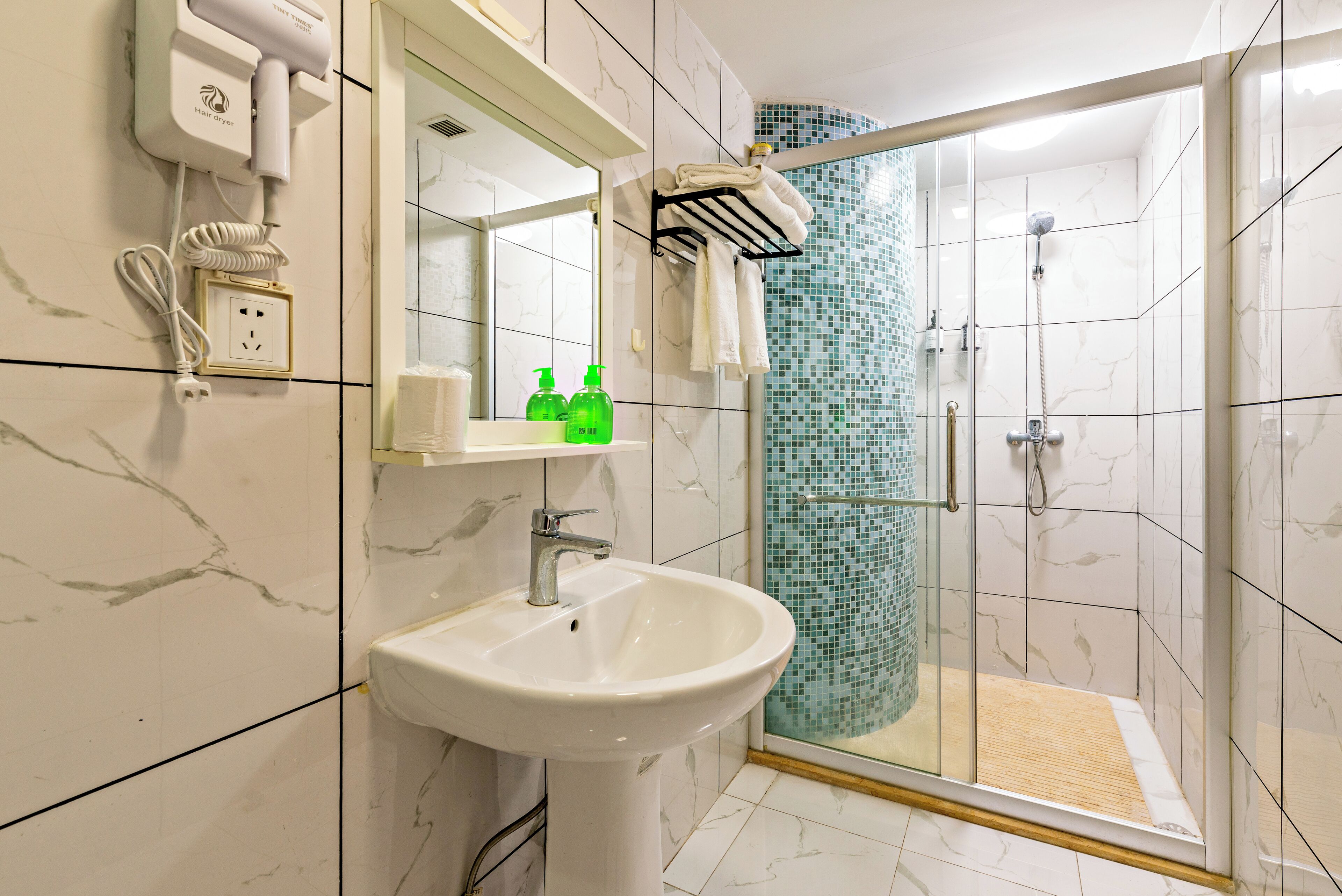 A bathroom with a white sink, a mirror, a towel rack, and a shower with a glass door.