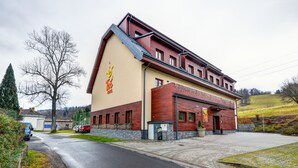 Un hotel con un letrero grande, una zona de estacionamiento y un edificio de techo inclinado.
