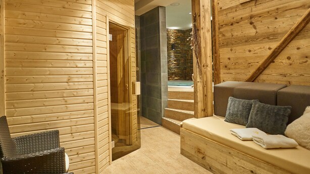 Interior de madera con un sofá y una puerta de vidrio que da a una pared de piedra.