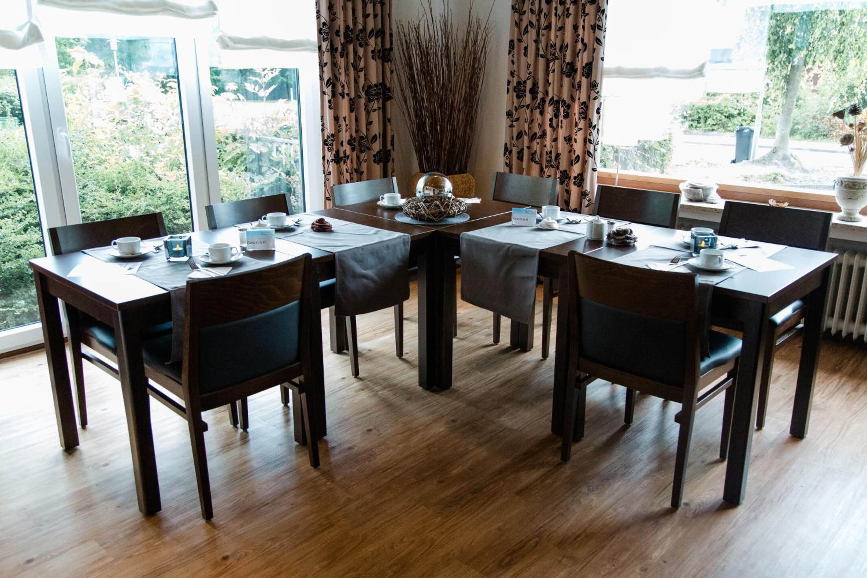 Un comedor con una mesa de madera dispuesta para seis personas, rodeada de sillas.