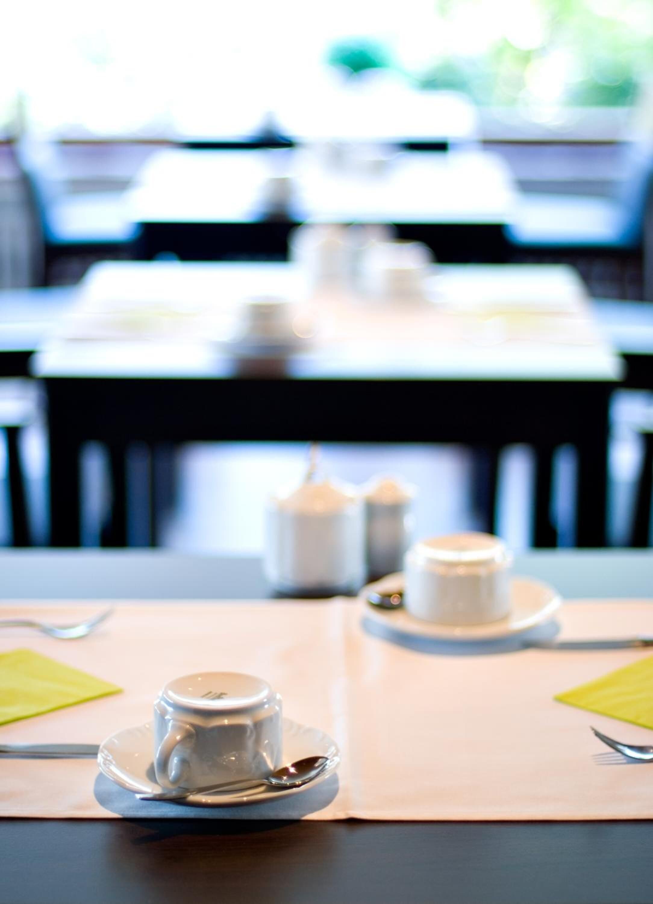 A dining table with a cup and saucer, a spoon, and a napkin.