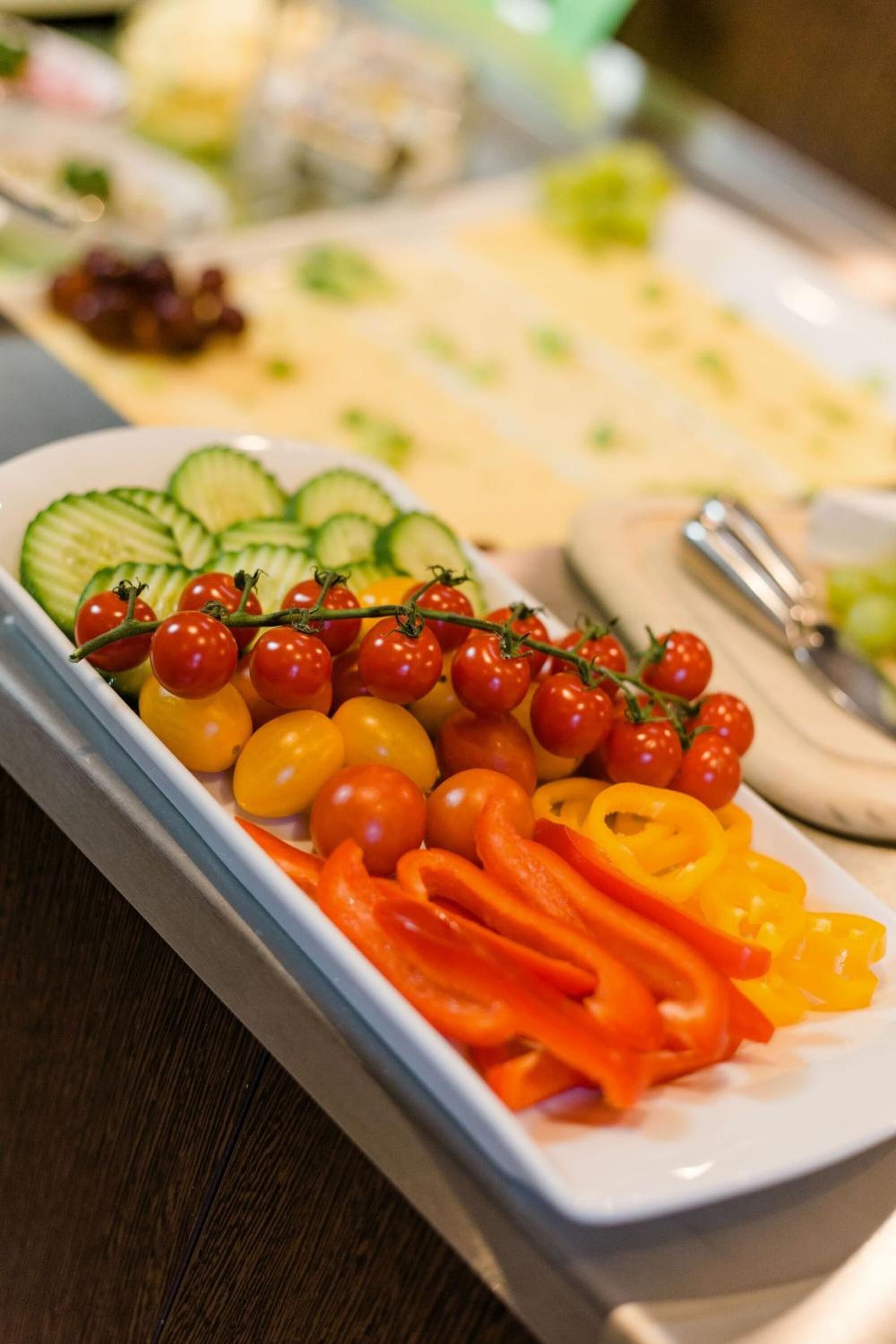 A tray of assorted vegetables including cherry tomatoes, cucumbers, and bell peppers.