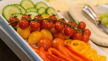 A tray of assorted vegetables including cherry tomatoes, cucumbers, and bell peppers.