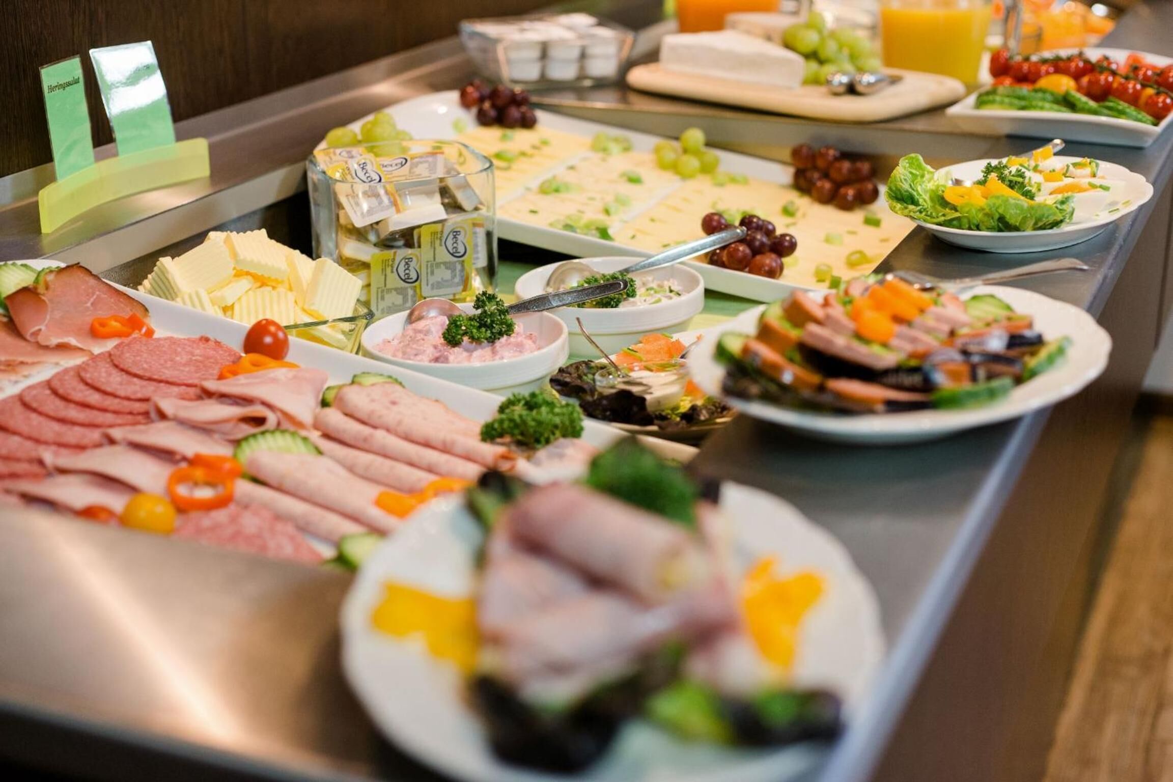 A buffet with various food items including meats, cheeses, and salads.