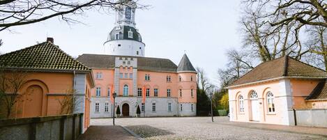 A historic building with a central tower, a courtyard with cobblestone paths, and adjacent smaller structures.