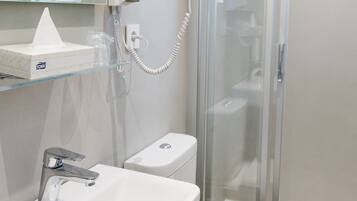 Un baño con ducha de vidrio, lavamanos blanco y retrete.