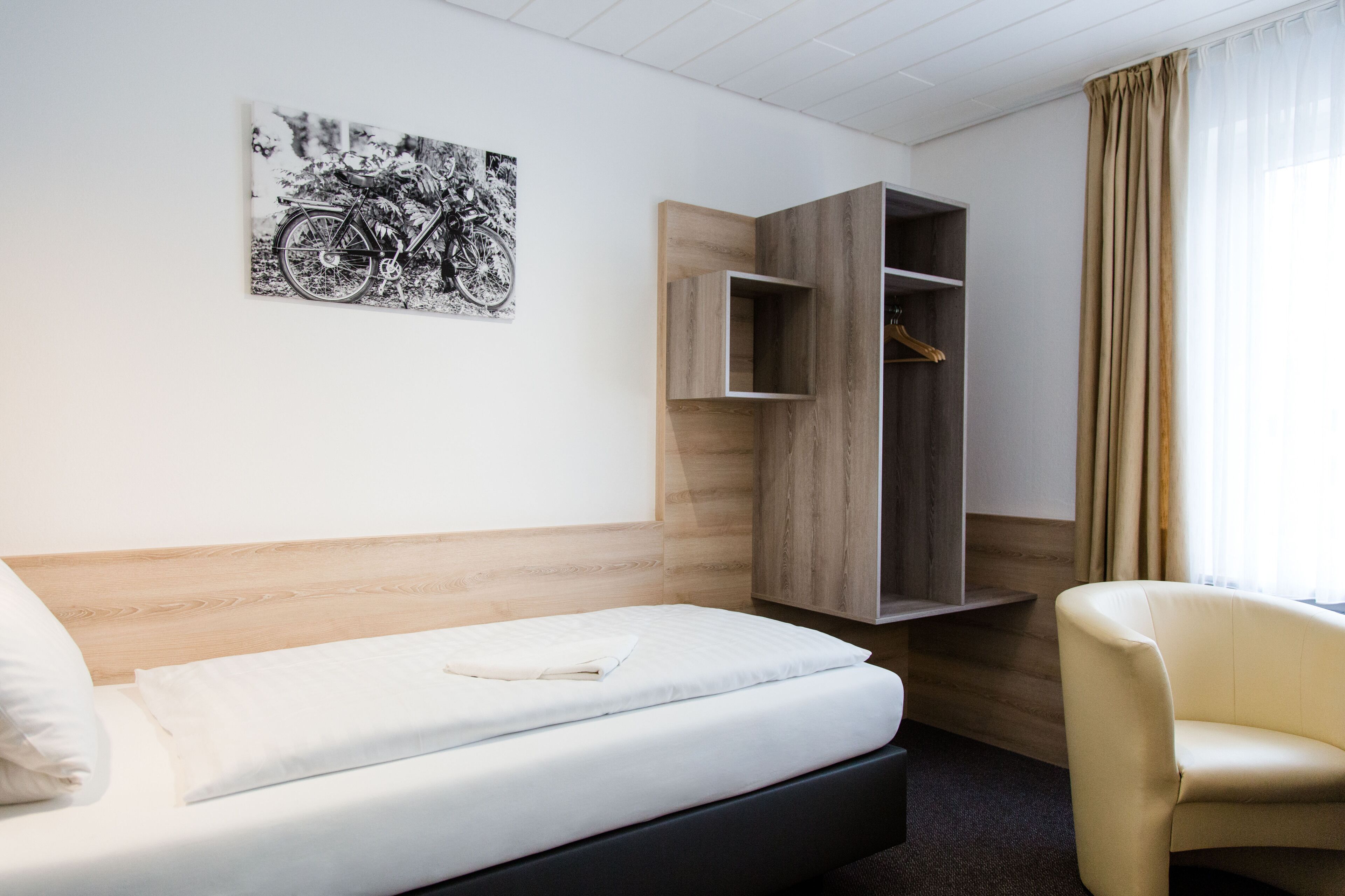 Une chambre d’hôtel comprenant un lit, une chaise, une armoire et une œuvre d’art accrochée au mur.