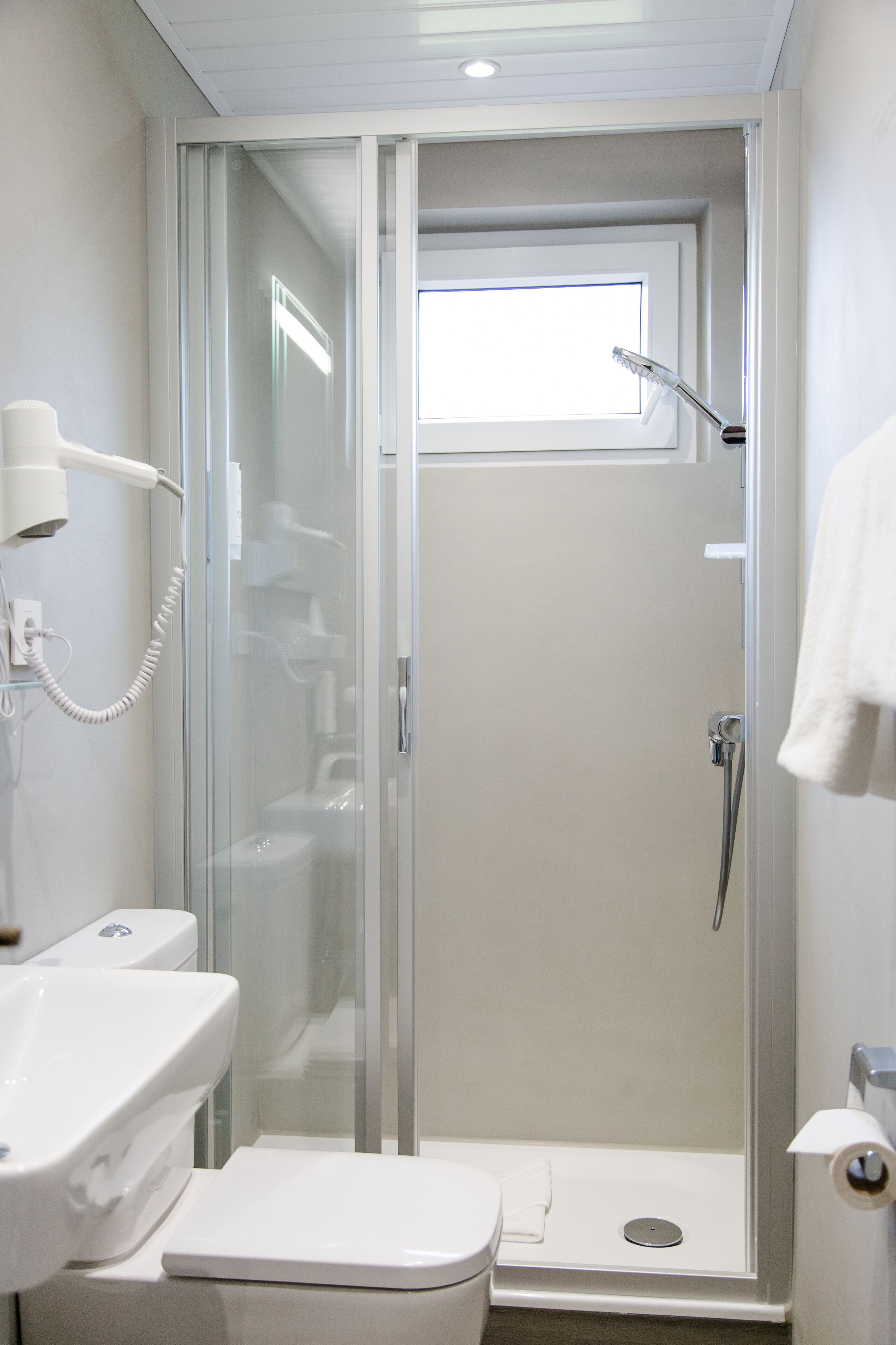 Un baño moderno con ducha acristalada, lavabo blanco y retrete.