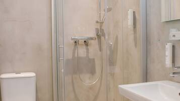 A modern bathroom with a glass-enclosed shower, a white toilet, and a sink.