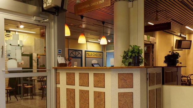 A reception area with cork bulletin boards, a sign for 'MILK: CHEESE', and a reception desk. - Laitilan Kievari (Laitila)