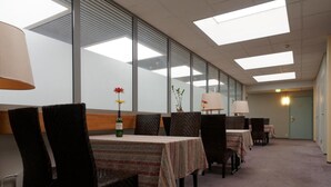 A dining area with tables and chairs, large windows, and ceiling lights. - Laitilan Kievari (Laitila)