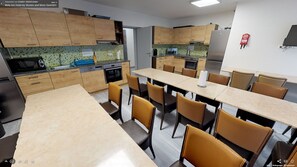 Una cocina moderna con armarios de madera, un comedor con sillas color beige y un refrigerador de acero inoxidable.