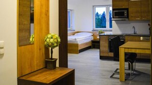 Een modern, compact appartement met een kitchenette, een eethoek en een slaapkamer met een groot raam.