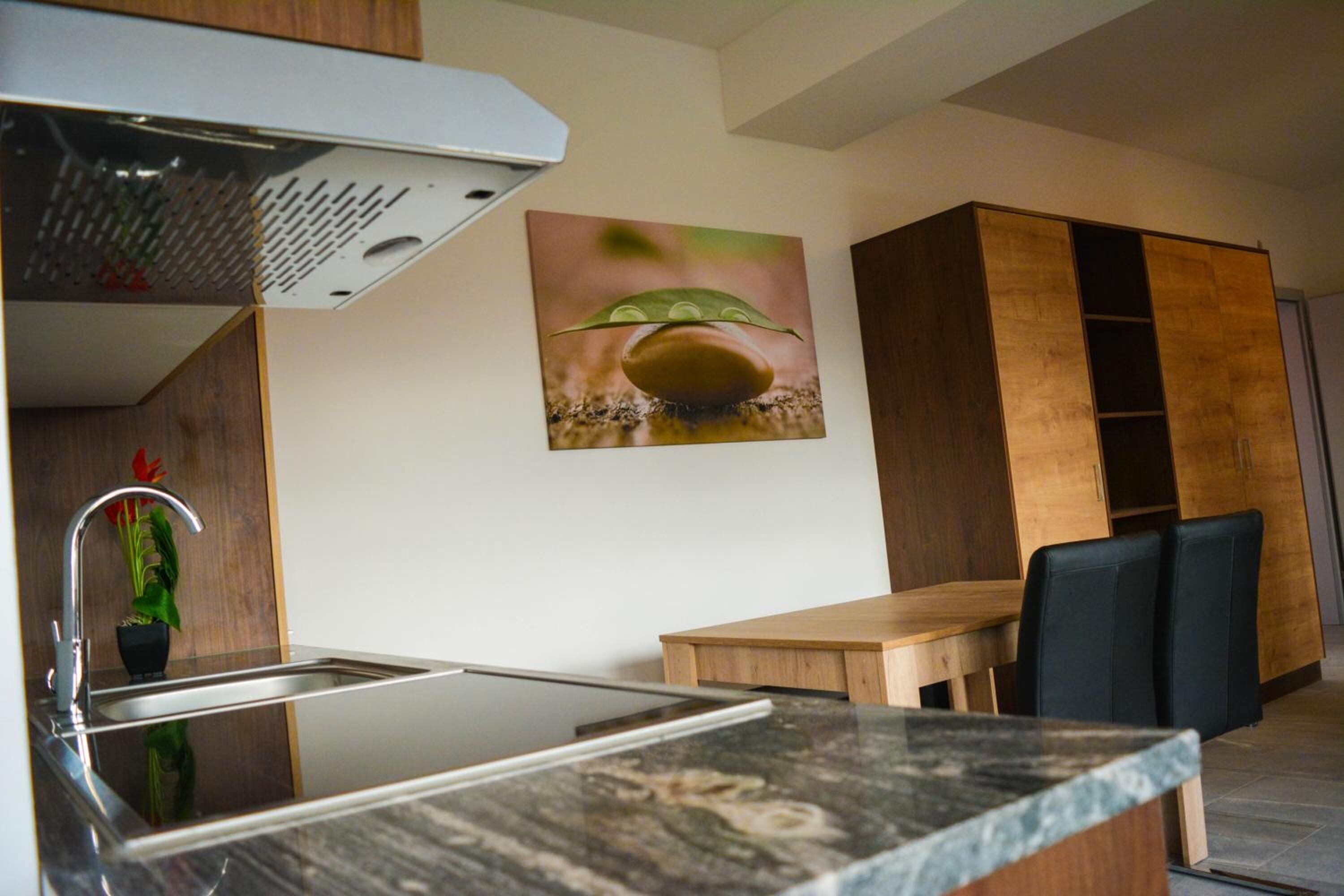 A modern kitchen with a stainless steel sink, a wooden cabinet, and a dining area with a table and chairs.