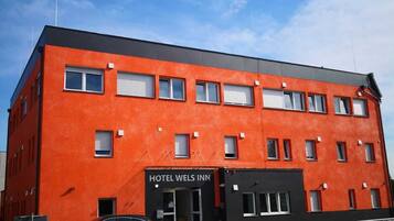 Hotel Wels Inn features a vibrant facade and symmetrical windows with shutters.