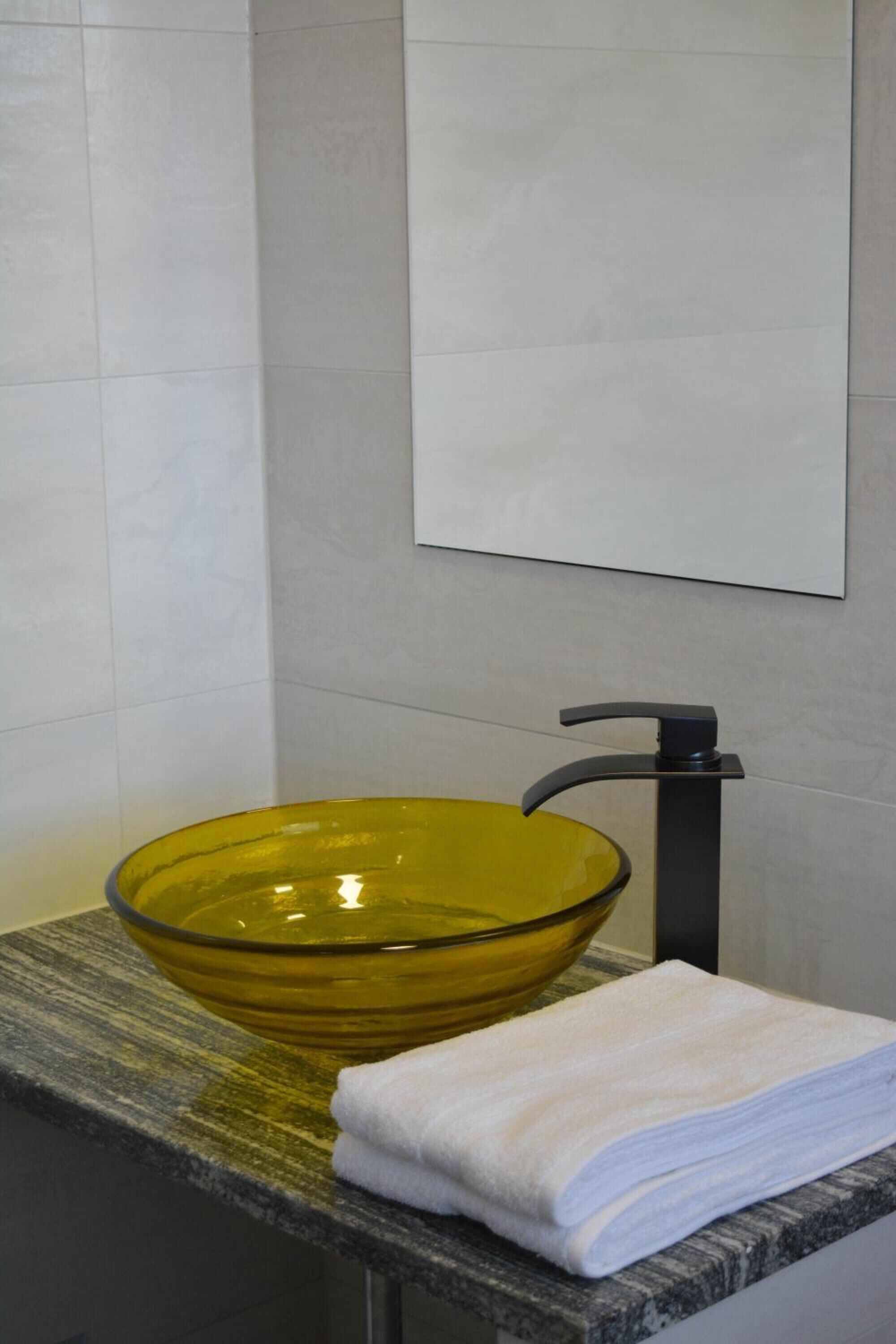 A bathroom with a glass bowl sink, a towel, and a mirror on the wall.