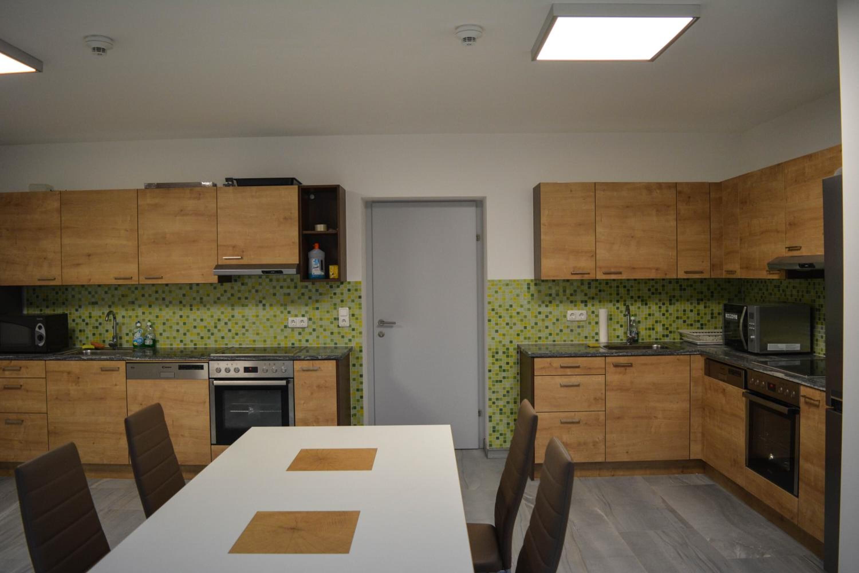 A compact kitchen with wooden cabinets, a dining table with chairs, and a microwave.
