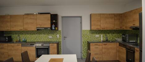A compact kitchen with wooden cabinets, a dining table with chairs, and a microwave.
