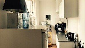 Une cuisine compacte équipée d’un réfrigérateur, d’un grille-pain, d’une machine à café et d’un évier.