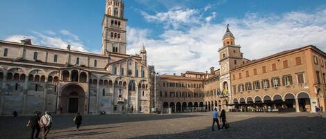 Una plaza histórica con una iglesia destacada, que cuenta con un campanario alto y una torre más pequeña adyacente.