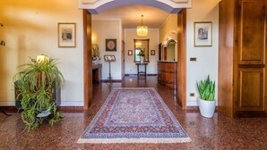 A hallway with a patterned rug, wooden doors, and framed pictures on the walls. - Hotel Aquila (Castelfranco Emilia)