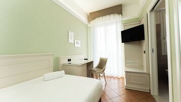 Une chambre d’hôtel avec un lit, un bureau, une chaise, une télévision et une porte de salle de bain.