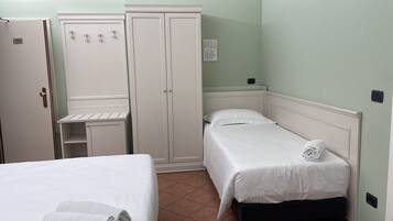 Une chambre avec un lit simple, une armoire et un bureau.