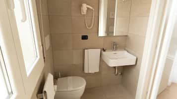A modern bathroom with a toilet, bidet, sink, and mirror.