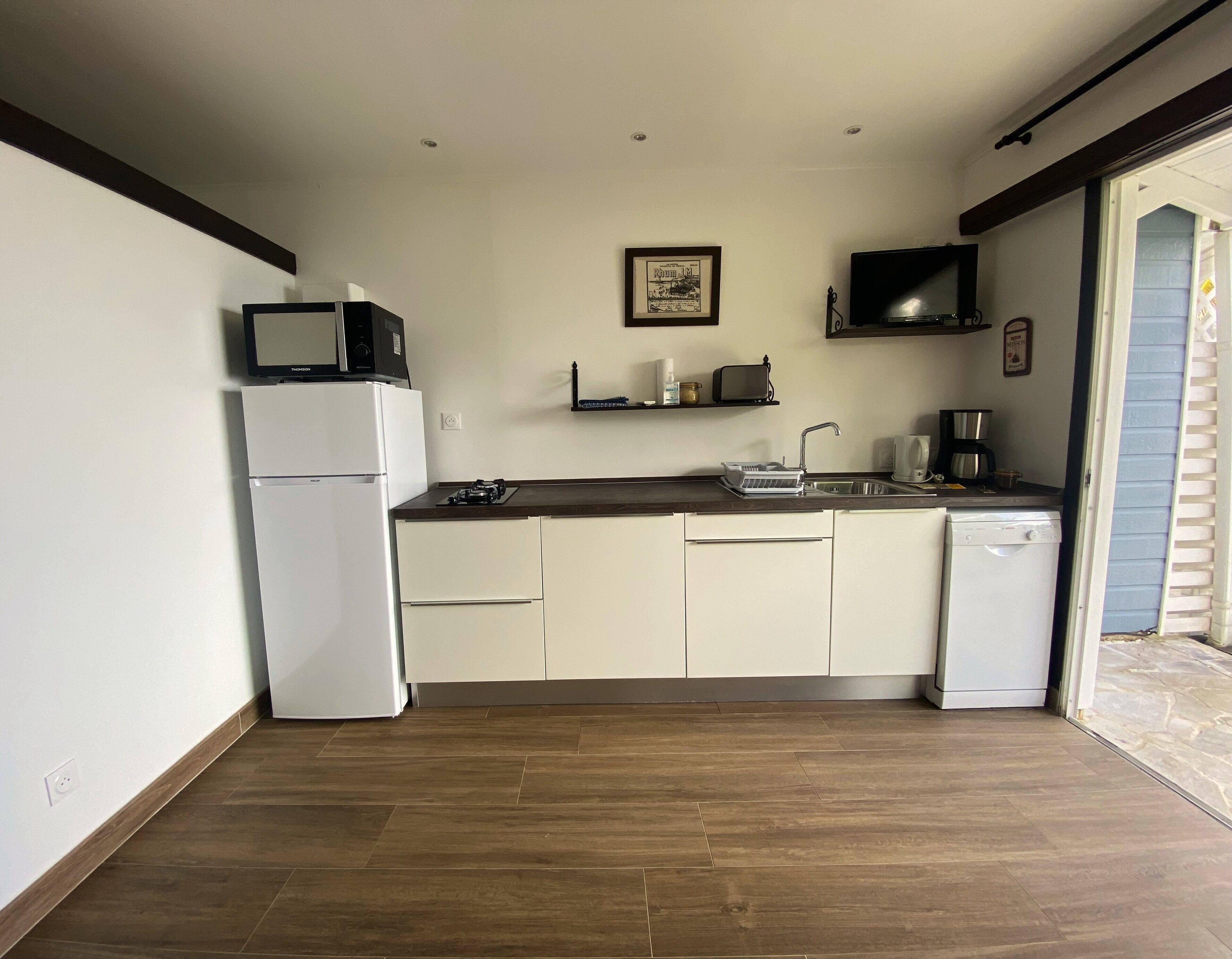 A compact kitchen with white cabinets, a built-in dishwasher, a microwave, and a coffee maker.