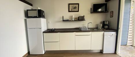 A compact kitchen with white cabinets, a built-in dishwasher, a microwave, and a coffee maker.