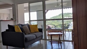 Ein modernes Wohnzimmer mit einer Couch, einem Tisch und einem Balkon mit Stühlen.