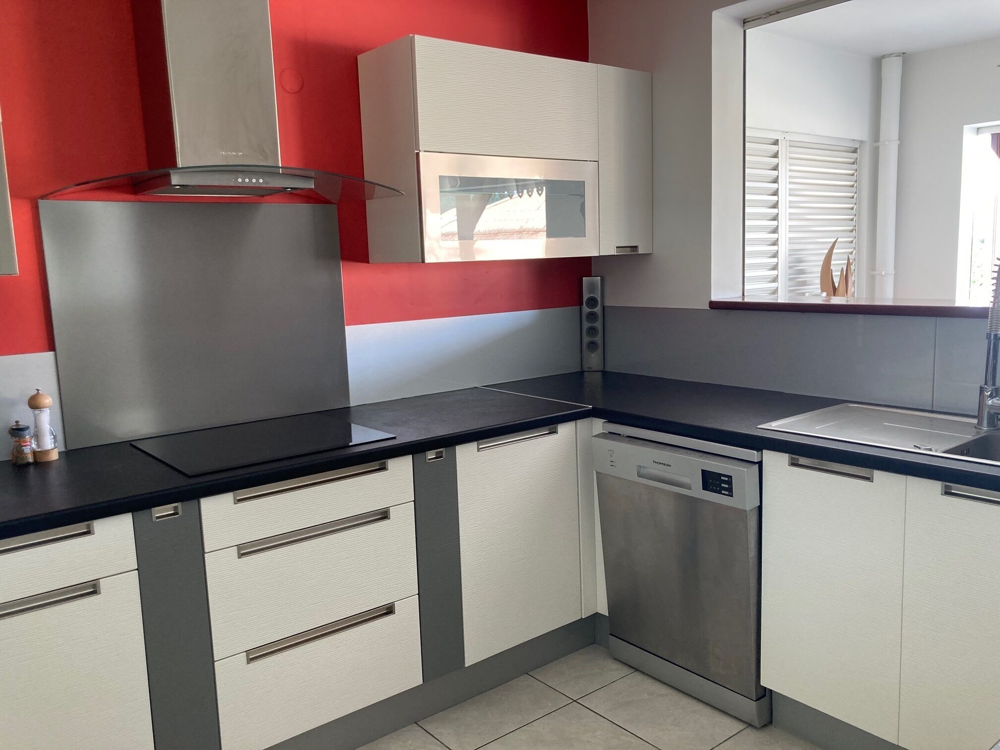 A modern kitchen with stainless steel appliances, white cabinets, and a black countertop.