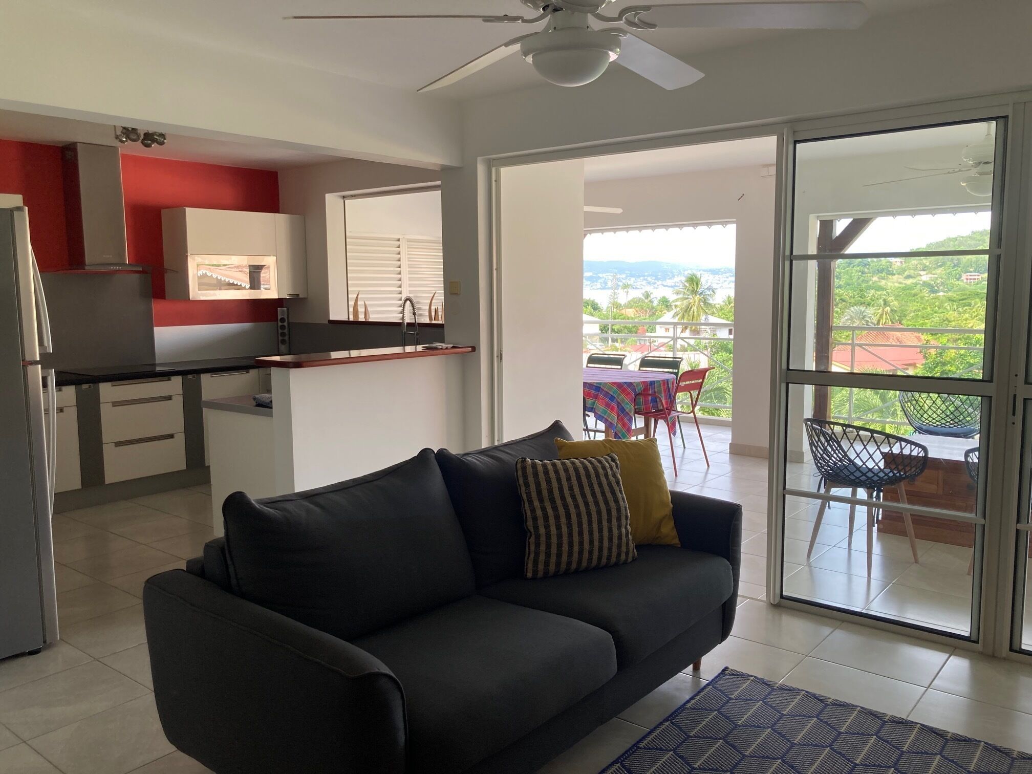 Una sala de estar con sofá, un comedor con mesa y sillas, una cocina con refrigerador, y un balcón con vistas.