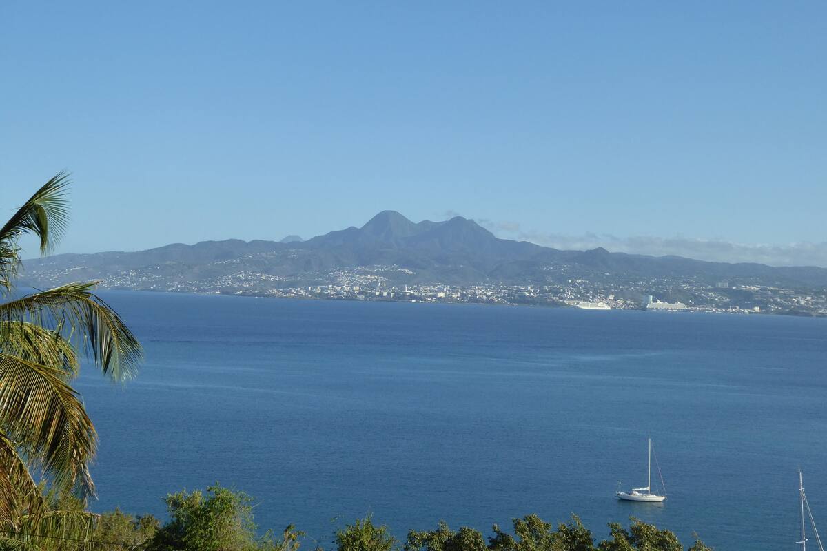 A coastal cityscape with a clear view of the ocean and a mountain range in the background.