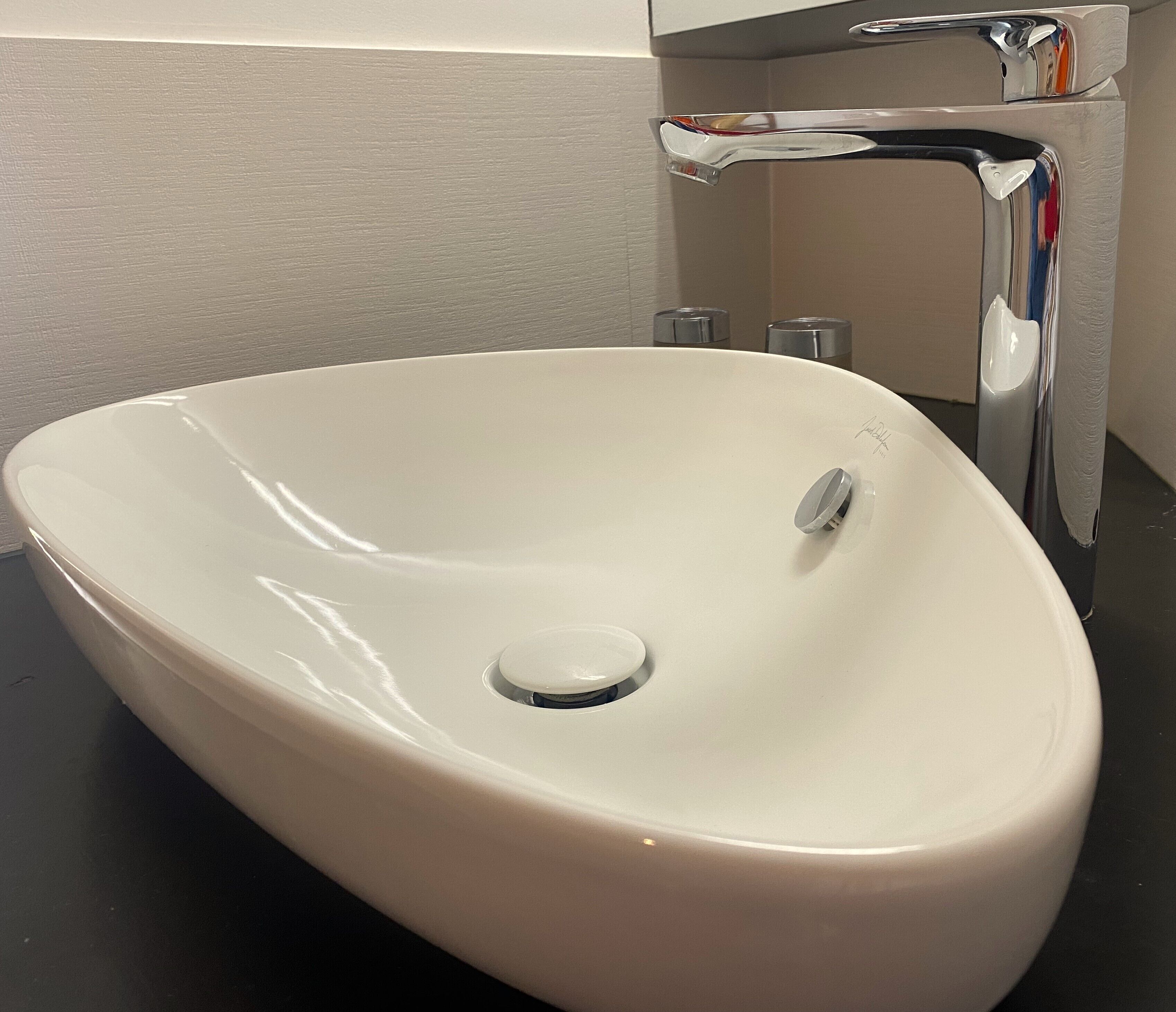 A white ceramic sink with a single faucet and a drain.
