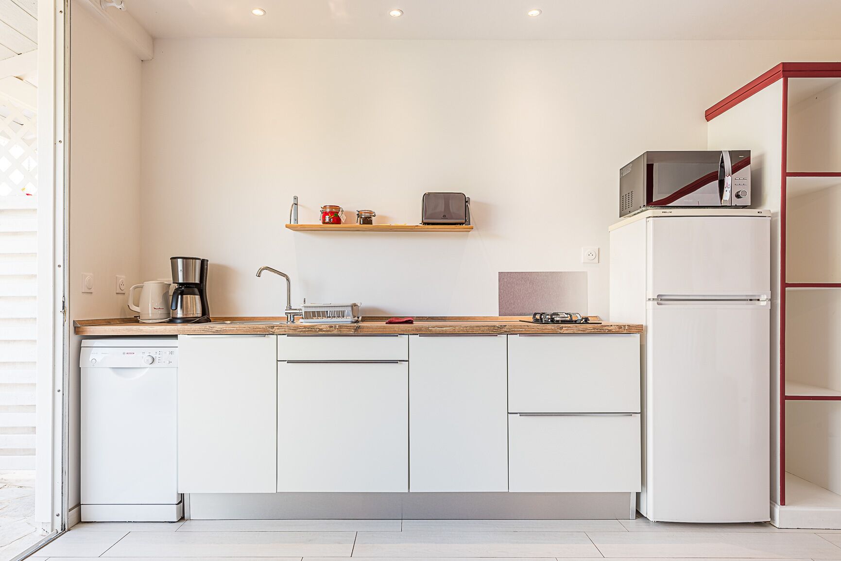 A compact kitchen with white cabinetry, a coffee maker, a microwave, and a toaster.