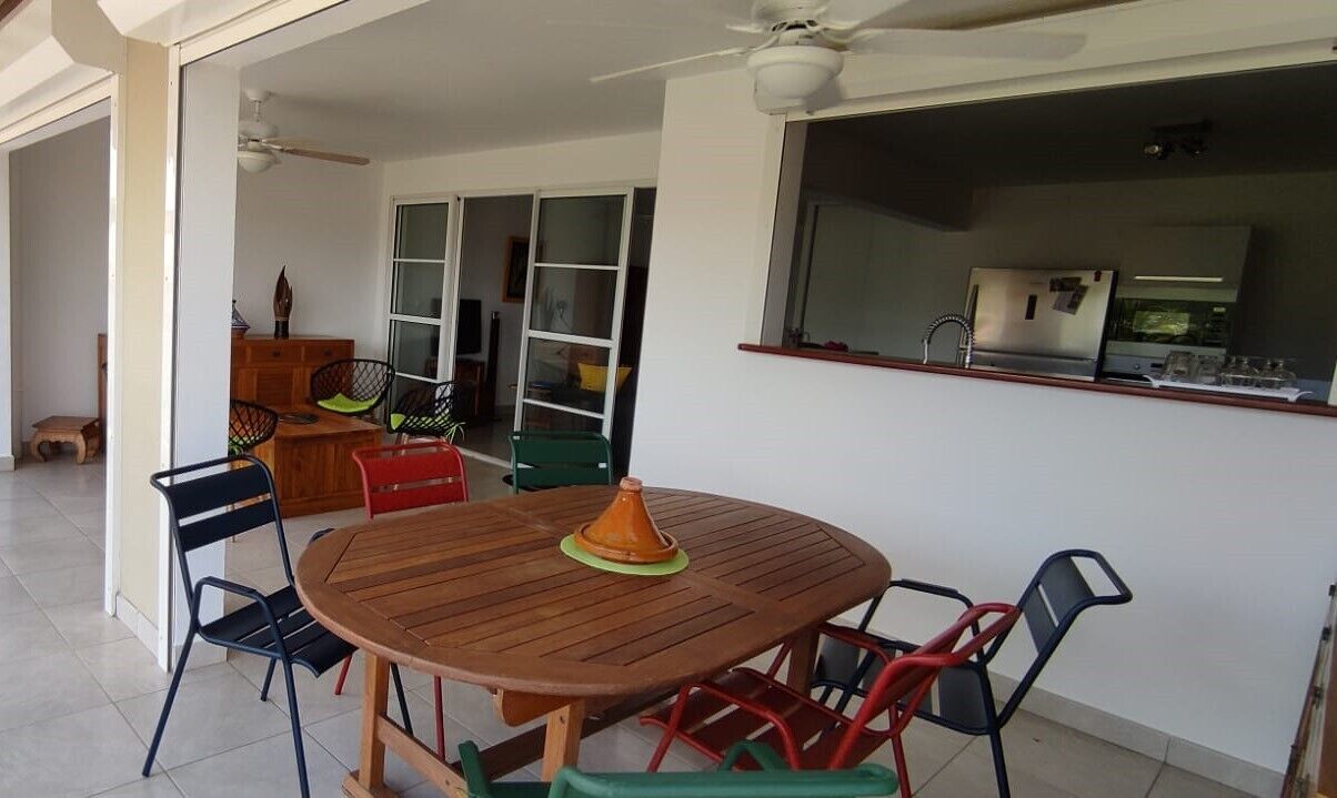 Un coin repas avec une table ronde en bois, des chaises et un ventilateur de plafond.