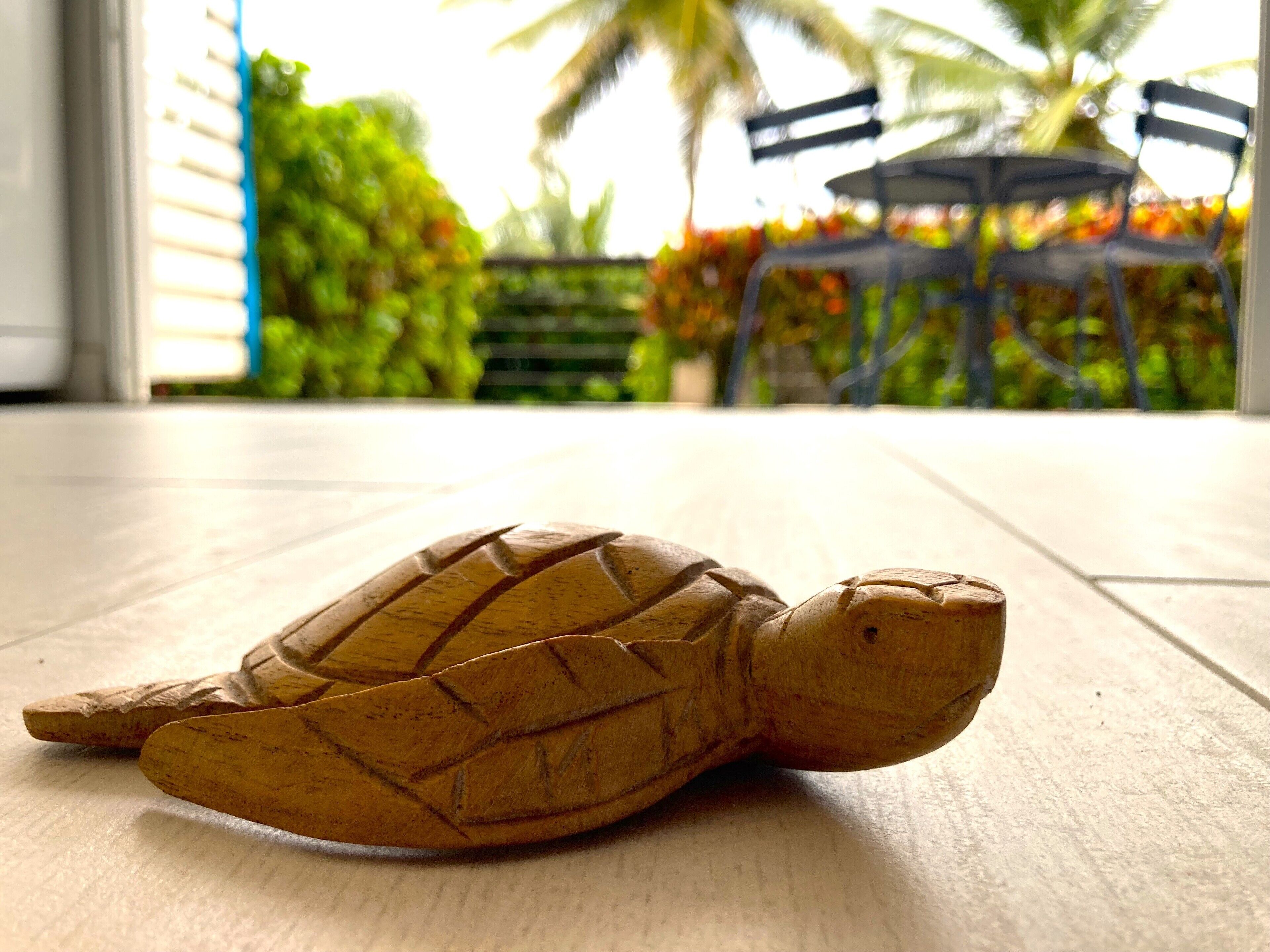 A wooden turtle sculpture on a tiled floor.