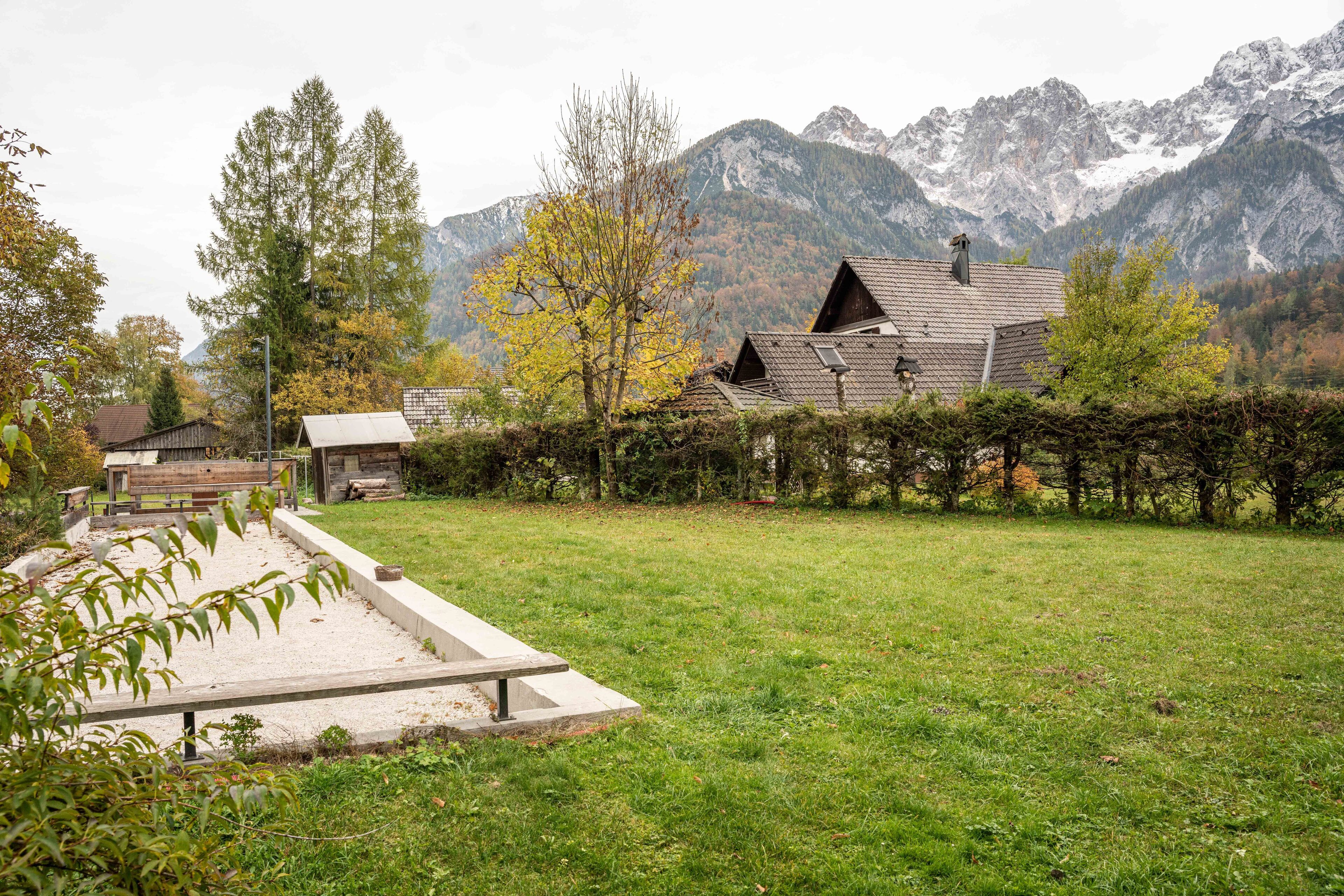 Ein Haus mit geneigtem Dach, umgeben von einem gepflegten Rasen und einem Holzzaun.