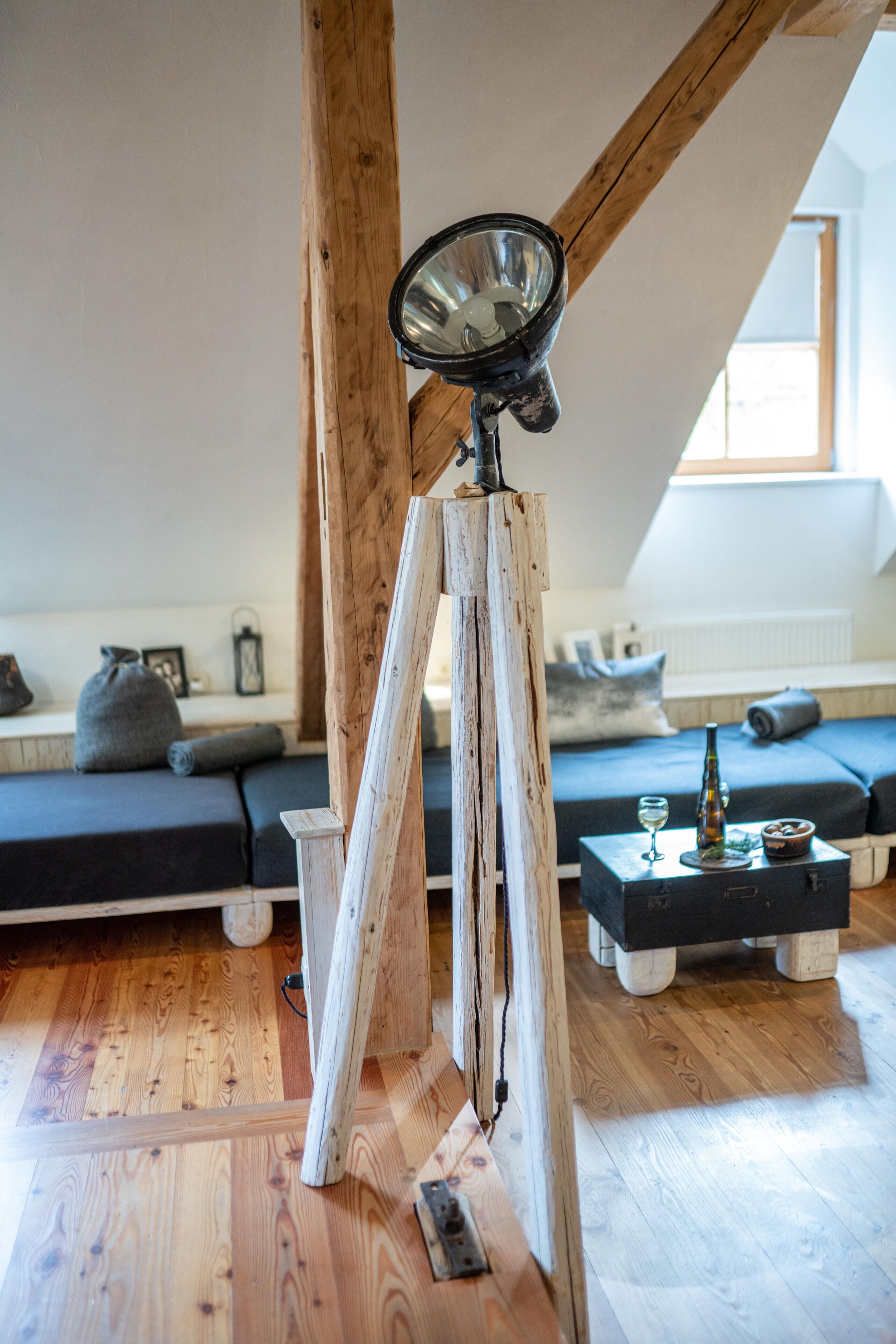 Ein Loft-Zimmer mit freiliegenden Holzbalken, einem Teleskop, einer Couch und einem kleinen Tisch mit Flasche und Glas.