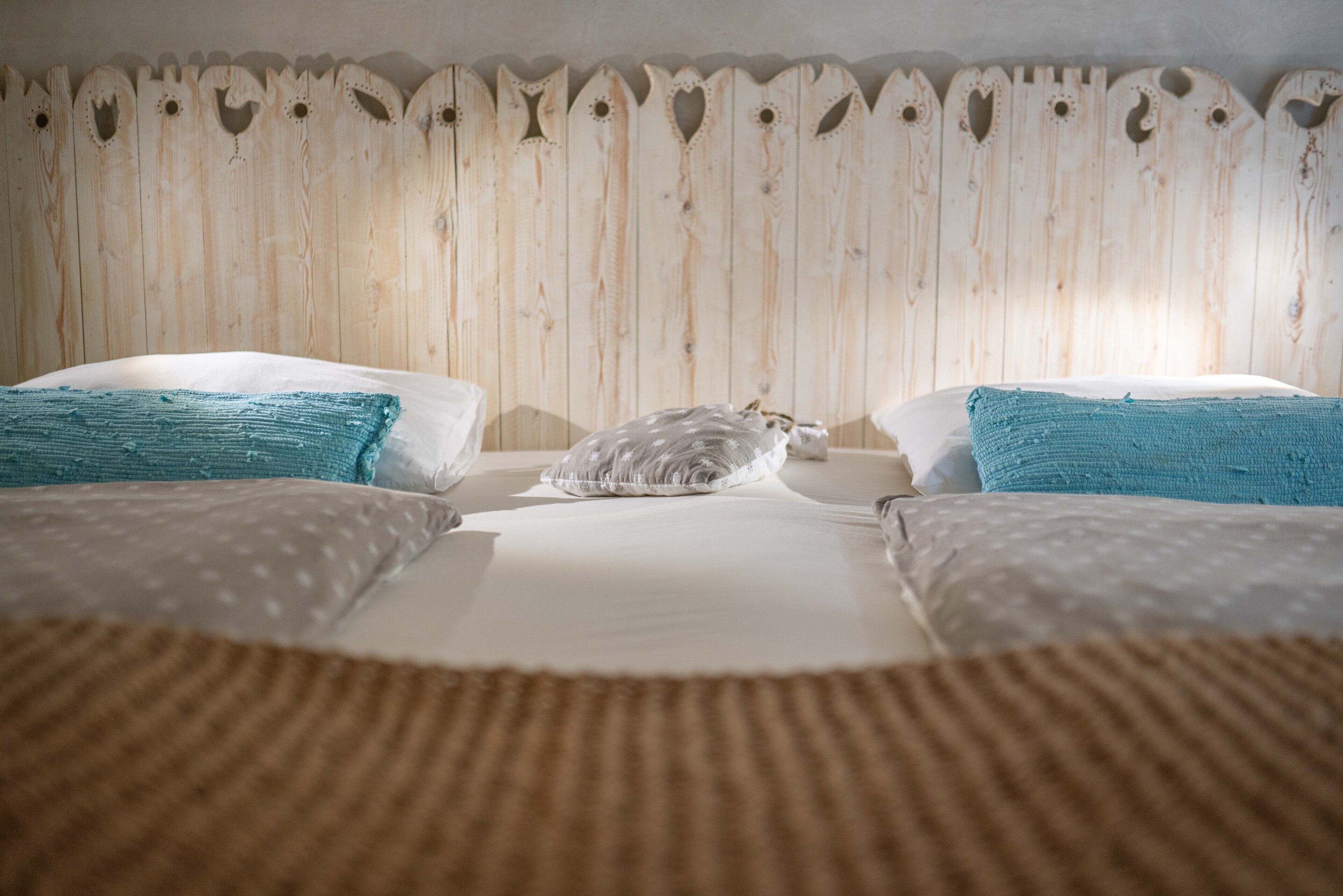 A bedroom with two beds, a wooden headboard, and a cat on one of the beds.