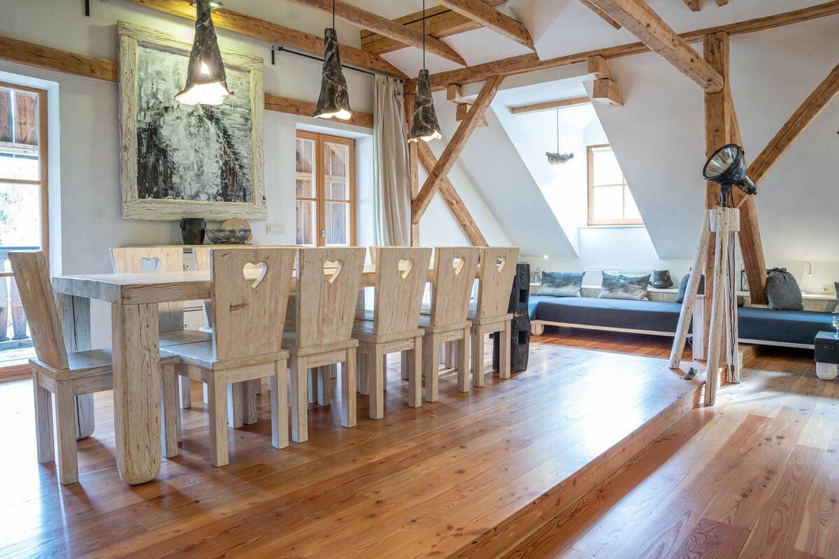 Ein rustikales Interieur mit Holzkunst, einem großen Gemälde und einer schrägen Decke mit freiliegenden Balken.