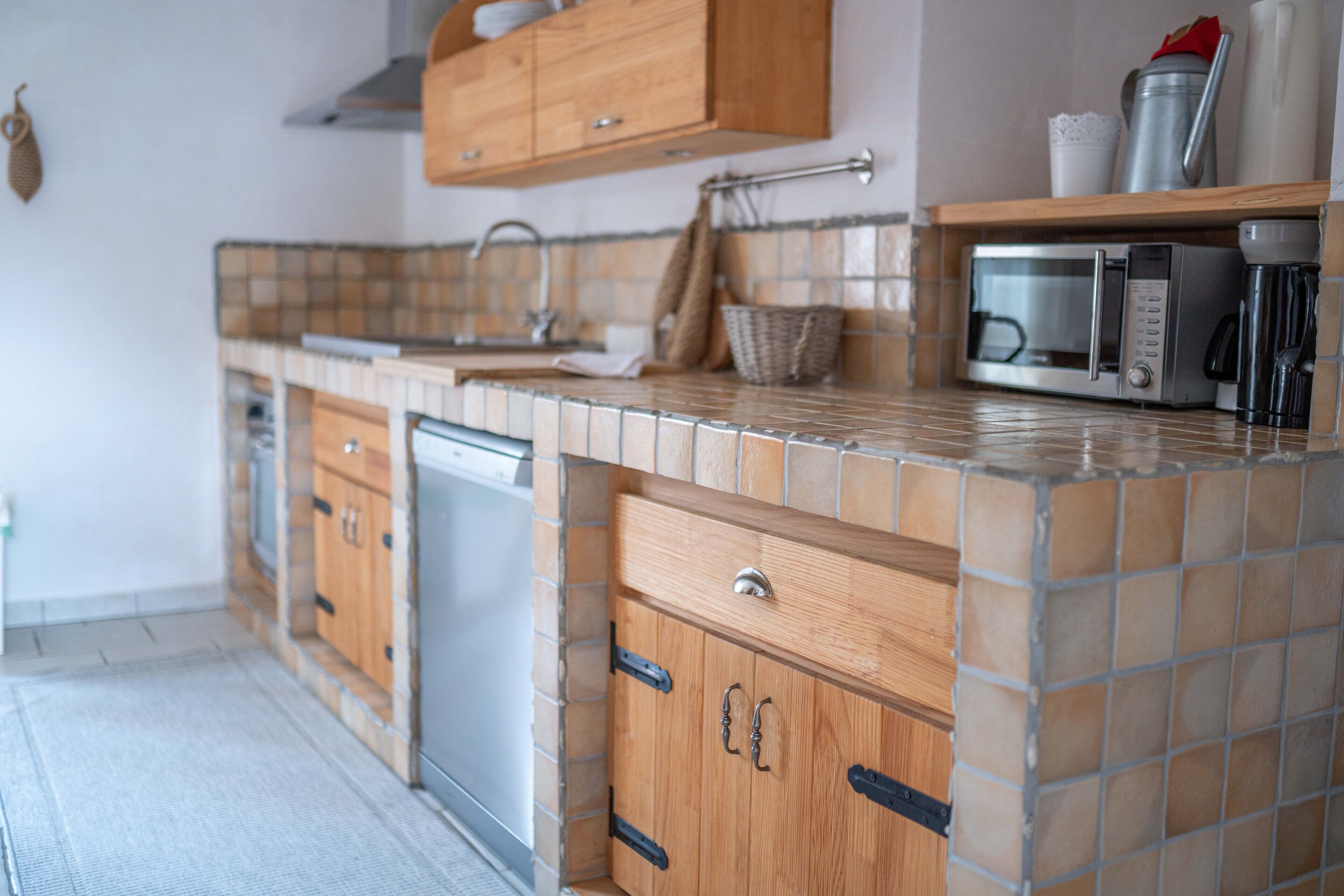 A kitchen with a tiled backsplash, wooden cabinets, a microwave, and a coffee maker.