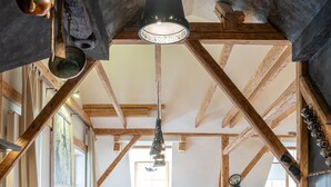 Eine rustikale Küche mit Holzbalken, ein Essbereich mit Holztisch und -stühlen sowie ein Blick ins Wohnzimmer.