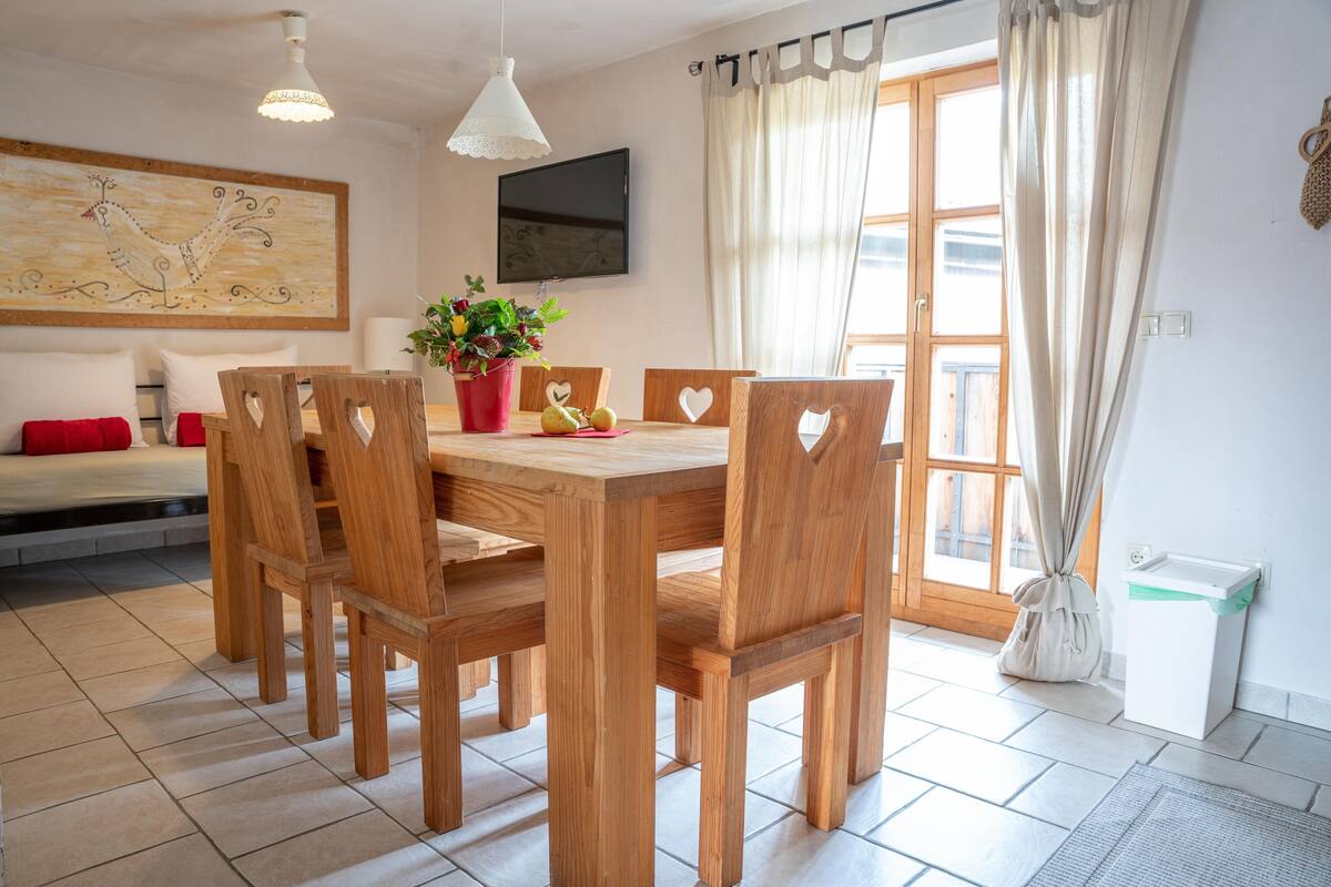 Ein Essbereich mit Holztisch und -stühlen, einer Topfpflanze und einem Bild an der Wand.